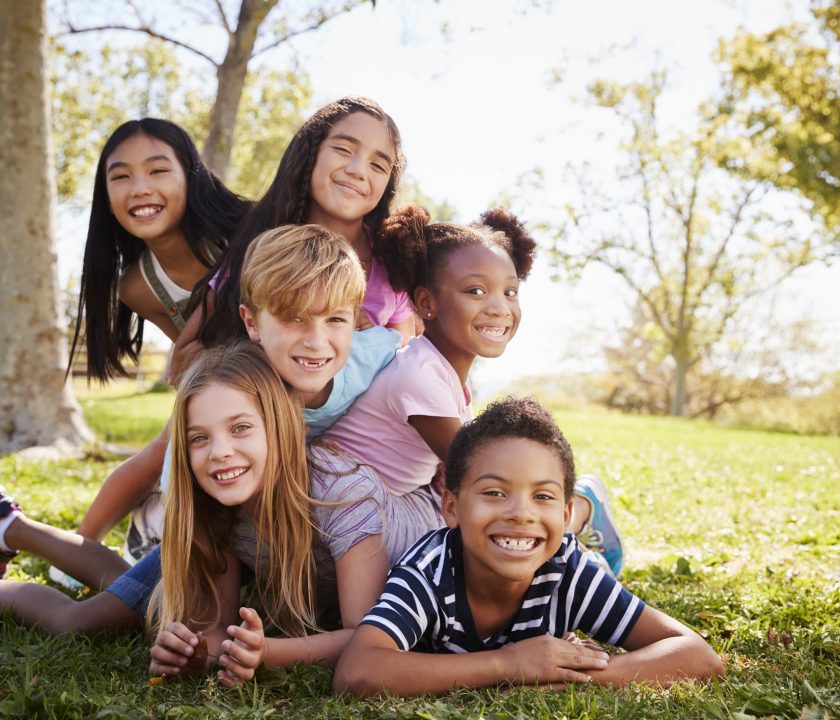 Multi-ethnic group of kids lying on each other in a park